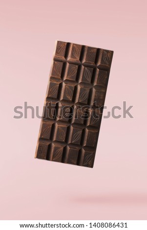 Flying in air tasty dark chocolate on pastel pink background. High resolution image