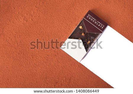 Tasty dark chocolate laying over cocoa powder background with empty space for your text. High resolution image