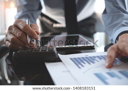 Business analysis, investment and finance concept. Businessman, accountant using calculator to calculate business report, marketing data, financial graph, spreadsheet and digital tablet on office desk