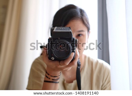 Asian young woman taking a photo with medium format film camera