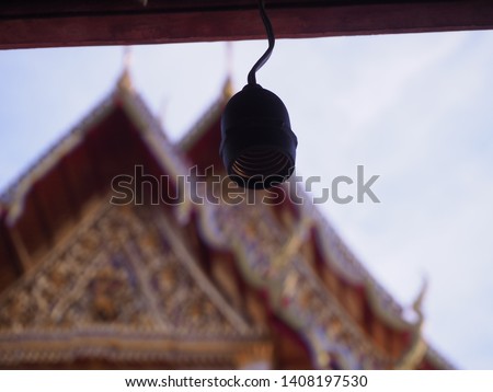 The light bulb illuminates the temple. An off light bulb with blur Buddhist temple in the background in Bangkok, Thailand.