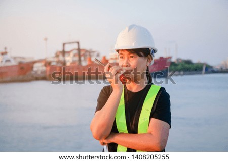 Female engineer wearing a white safety helmet holding a red radio for communication