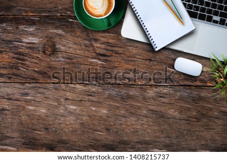 office supplies laptop, smartphone, notepad, and coffee cup on a wooden table background. View from above.