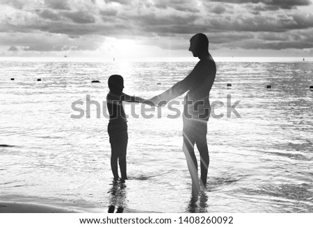 Father and daughter silhouettes at sunset on the beach.