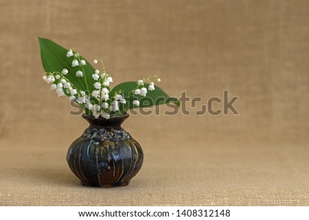 Bouquet of May lily of the valley in a ceramic vase on a natural blurred background with copy space