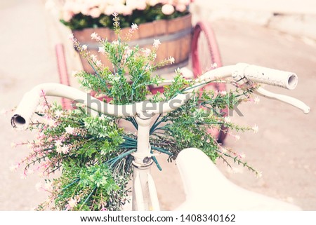 Rusty vintage white bike with basket of flowers against blured backround