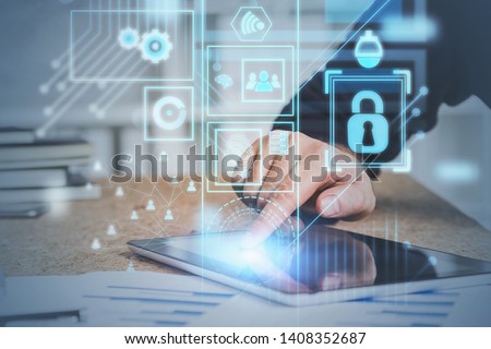 Hand of man in suit using tablet computer in office with double exposure of online security interface and social media icons. Concept of data protection. Toned image
