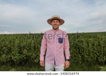 Young stylish farmer in a hat on the background of his fields
