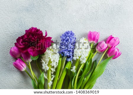 Beautiful bouquet of fresh tulips, peony and hyacinth on a light stone background. Top view, copy space