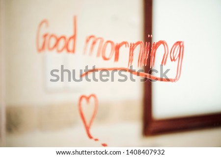Image of text Good morning written with red lipstick on the mirror in bathroom