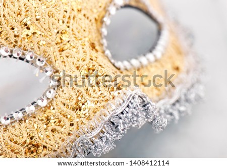 Close up macro image of a decorative gold and silver mask embellished by diamonds, isolated on a white background