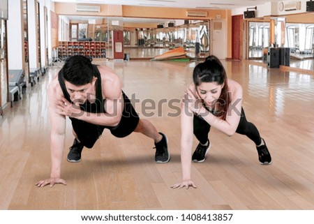 Picture of young couple doing plank exercises together in the fitness center