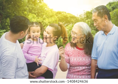 Picture of multi generation family looks cheerful while chatting together and standing in the park