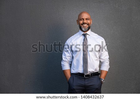 Portrait of successful black businessman standing against grey wall. Smilng senior entrepreneur in formal clothing looking at camera. Mature happy man isolated on grey background with copy space. Royalty-Free Stock Photo #1408432637