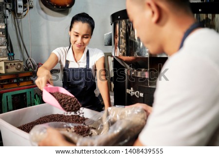 Young Asian couple working in team they packing fresh roasted coffee beans in bag for sale