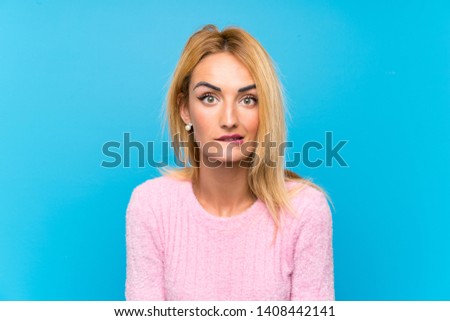Young blonde woman over blue background having doubts and with confuse face expression