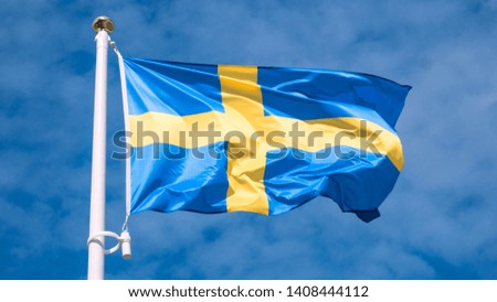 Swedish flag waving in sunny blue sky.