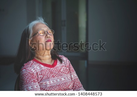 Picture of elderly woman falling asleep in a wheelchair. Shot in dark room