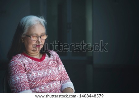Picture of a lonely old woman falling asleep in the wheelchair. Shot in dark room