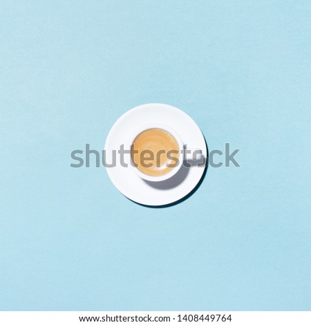 A cup of coffee on blue background. Trendy minimal styled flat lay photography with cappuccino.
