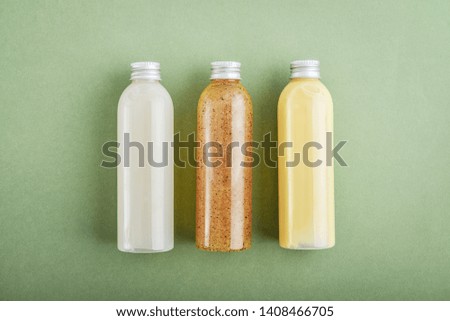 Bottles with spa cosmetic products on green background, top view. Beauty salon treatments concept.
