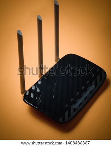 Black Three-antenna wi-fi router isolated on yellow background.