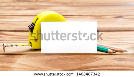 Blank business card with measuring tape tool and pencils on the table. Space for writing your contacts.