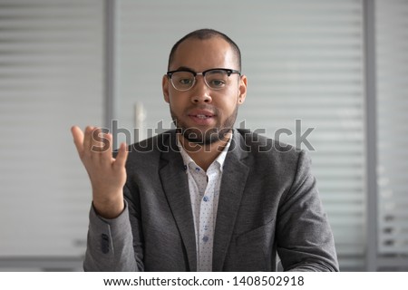 Serious african businessman entrepreneur in suit talking to camera, mixed race coach webinar speaker teacher trainer shooting vlog online business training look at webcam make conference video call Royalty-Free Stock Photo #1408502918
