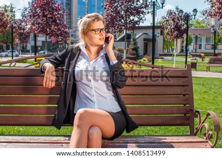 girl in business talking on the phone sitting on a bench
