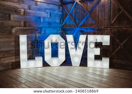 Wooden glowing love text letters. Rustic wedding dance floor lamp in a barn.