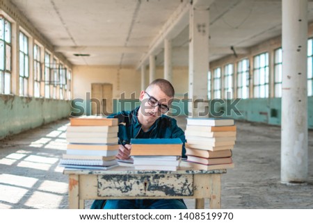 Photo of a student with a stack of books in front of him, preparing for the exam. Retro concept, old building