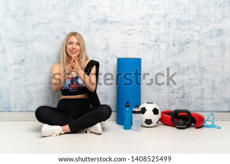 Young blonde sport woman sitting on the floor applauding