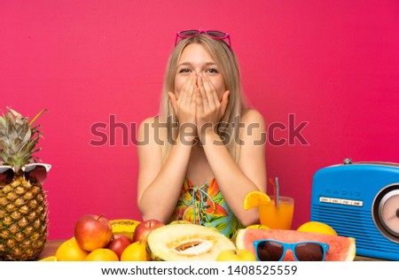 Young blonde woman with lots of fruits with surprise facial expression