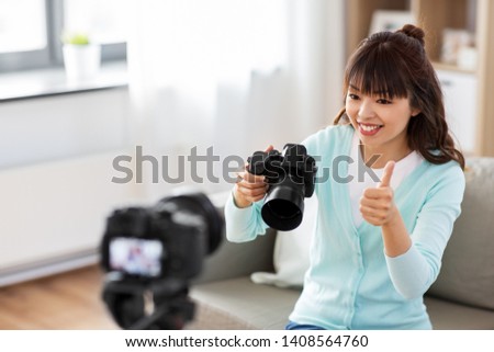 blogging, videoblog and technology concept - asian woman or blogger with photo camera recording video blog at home