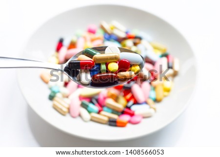 Various types of tablets, capsules and pills on  spoon with colorful medicine background. Top view