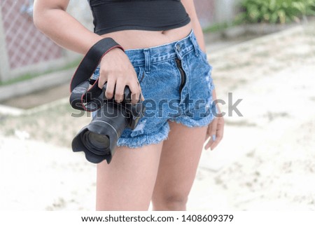 A female photographer holds a camera that is separated from the background.