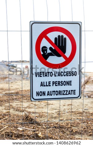 Warning sign reading: 'no entry unauthorised personnel' near a construction site on the shoreline in Follonica, Italy