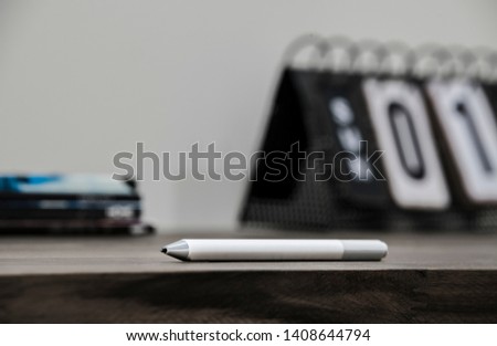 a business photo showing a creative drawing pen, rustic calendar and stacked books, all on top of a desktop. This is a photo aimed towards business people