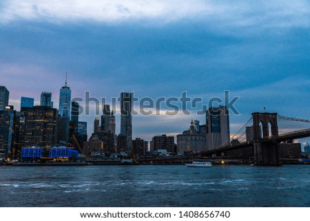 Skyline of the Brooklyn Bridge and modern skyscrapers of New York Financial District and the Lower Manhattan at night viewed from the Brooklyn Bridge Park in New York City, USA