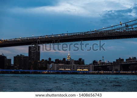 Skyline of the Brooklyn Bridge and modern skyscrapers of New York Financial District and the Lower Manhattan at night viewed from the Brooklyn Bridge Park in New York City, USA