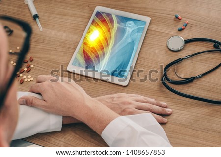 Doctor watching a digital tablet with x-ray of chest with pain on the heart. 