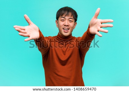 Young chinese man very happy giving a hug to the front