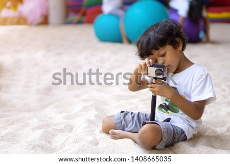 Asian boy using action camera to take a picture or video.