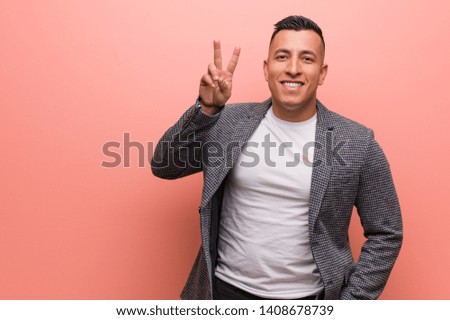 Young elegant latin man fun and happy doing a gesture of victory