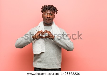Young fitness african black man smiling and showing a heart shape with him hands.