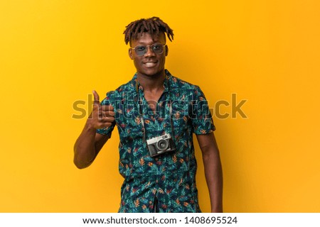 Young black rasta man wearing a vacation look smiling and raising thumb up