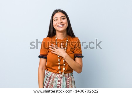 Young arab woman laughs out loudly keeping hand on chest.
