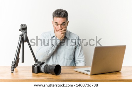 Young handsome photography teacher thoughtful looking to a copy space covering mouth with hand.