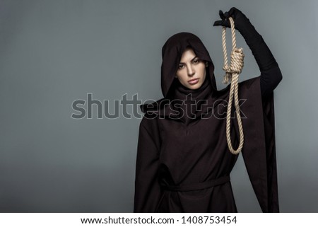 woman in death costume holding hanging noose isolated on grey