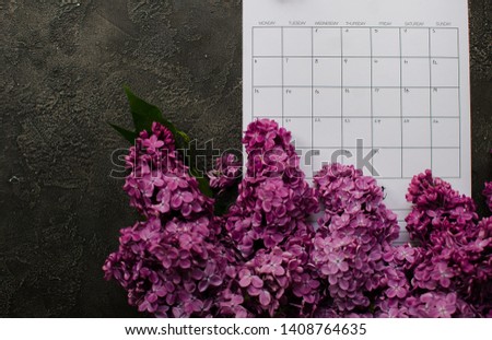 empty calendar with lilac flowers. flat lay pictures. dark wooden background 